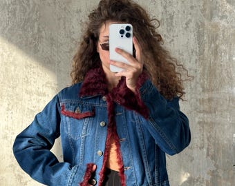 Peut inclure: Une veste en jean bleu dotée d'un col, de poignets et d'un ourlet en fausse fourrure bordeaux foncé. La veste comprend une fermeture boutonnée sur le devant, deux poches poitrine à rabat boutonné et des manches longues. La doublure est en fausse fourrure.
