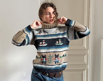 May include: A long-sleeve turtleneck sweater featuring horizontal stripes in shades of tan, gray, black, and blue. The knit pattern includes graphic motifs of birds, figures in small boats, and stylized cats, paired with blue denim jeans.