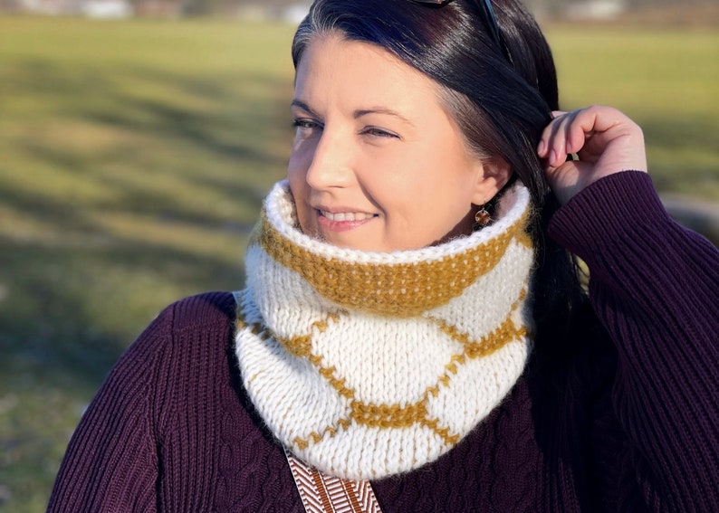 Reversible Cream and Gold Tunisian crochet cowl with hexagon motif, worn by dark haired woman in purple sweater, tucking hair behind ear