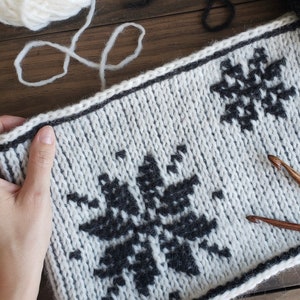 White reversible Tunisian Crochet cowl with black snowflake motif, laid flat.