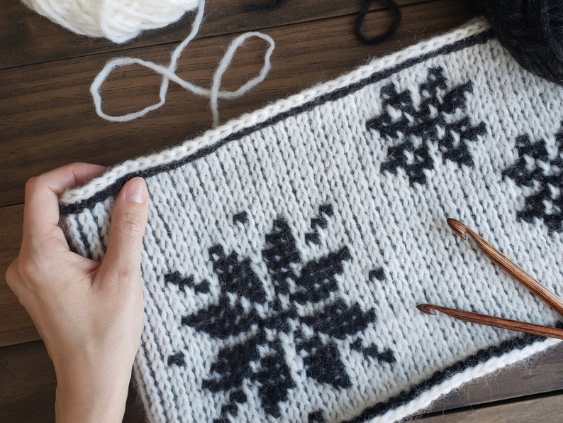 White reversible Tunisian Crochet cowl with black snowflake motif, laid flat.