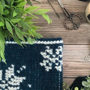 Closeup of corner of dark blue Tunisian Crochet Cowl with white snowflake motif.