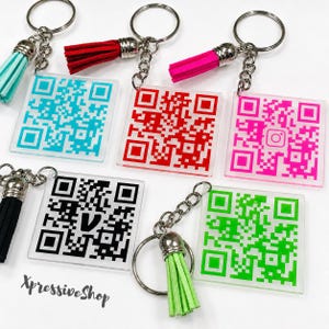May include: Five square acrylic keychains with metal rings and colorful tassels. Each keychain features a unique QR code in cyan, red, hot pink, black, or lime green. The black keychain displays a V logo, and the pink one shows an Instagram icon.