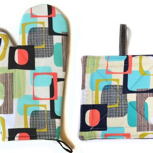 May include: A set of two kitchen pot holders with a geometric pattern in shades of teal, yellow, red, black, and white. The pot holders are made of fabric and have a quilted design.