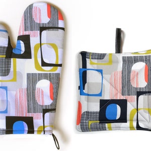 May include: A set of two oven mitts with a geometric pattern in shades of gray, blue, yellow, red, and black. The mitts are made of fabric and have a quilted texture.