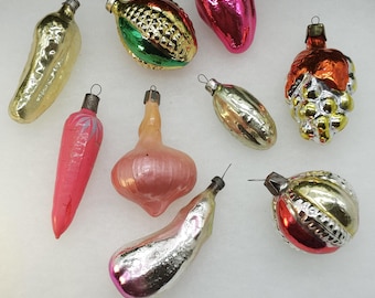 May include: Assortment of vintage glass Christmas ornaments shaped like vegetables and fruits. The ornaments are in various colors, including red, green, gold, silver, and pink.