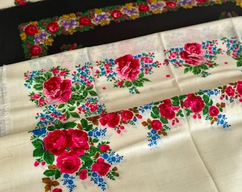 Pode incluir: Close-up de vários têxteis com padrões florais. Os têxteis apresentam um fundo creme, preto e branco com um padrão repetido de rosas vermelhas, flores azuis e folhas verdes. Os têxteis são dobrados e sobrepostos.