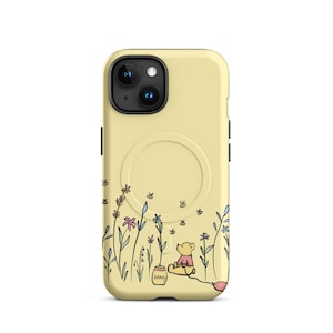 May include: A yellow iPhone case featuring a whimsical illustration of Winnie the Pooh. The design includes Pooh Bear sitting near a honey pot and a pink balloon, with a field of flowers and butterflies. The case has a MagSafe ring.