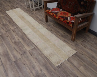May include: A long, off-white runner rug with a subtle pattern. The rug is laid out on a wood floor.