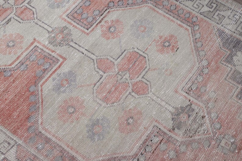 Puede incluir: Una alfombra vintage con un patr&oacute;n descolorido en rosa y gris. La alfombra tiene un dise&ntilde;o tradicional con detalles intrincados.