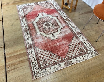 May include: A vintage red and cream area rug with a floral pattern. The rug has a distressed look and is perfect for adding a touch of bohemian style to your home.
