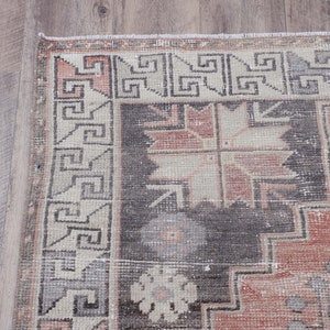 Puede incluir: Una alfombra vintage con un patr&oacute;n geom&eacute;trico en tonos de rosa, gris y blanco. La alfombra tiene un aspecto descolorido y desgastado, lo que le da un aspecto &uacute;nico y antiguo.