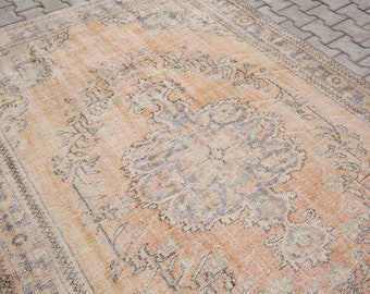 Puede incluir: Una alfombra vintage con un fondo melocotón descolorido y un patrón floral en tonos grises y beige.