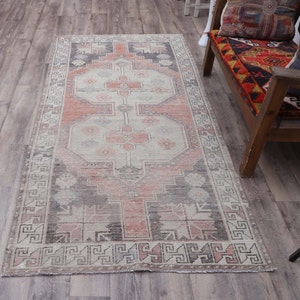 Puede incluir: Una alfombra turca vintage con un patr&oacute;n geom&eacute;trico tradicional en tonos de rosa, gris y blanco. La alfombra tiene un aspecto descolorido y desgastado, perfecto para agregar un toque de estilo bohemio a cualquier habitaci&oacute;n.