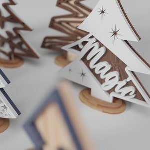 May include: Three wooden Christmas tree ornaments with different designs. One is brown with a snowflake pattern, one is blue with a snowflake pattern, and one is white with the word "Magic" on it.