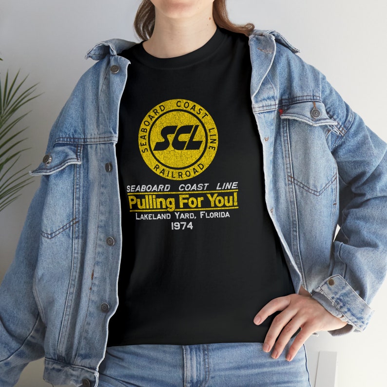 Lifestyle: woman in Black Seaboard Coast Line Railroad shirt with denim jacket, facing left