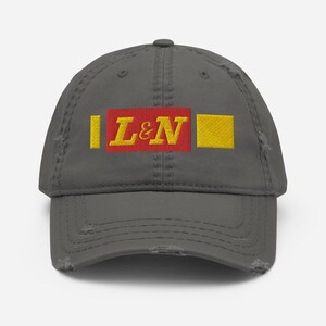 May include: A gray distressed baseball cap with a red and yellow embroidered patch that says "L&N".