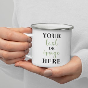 May include: White enamel mug with a silver rim. The mug has black text that says "YOUR text OR image HERE" with the words "text" and "image" in a green font.