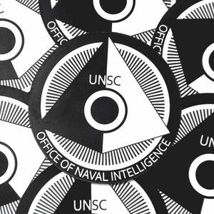 Puede incluir: Una colección de pegatinas circulares en blanco y negro. Cada pegatina presenta un diseño segmentado con el texto "UNSC" y "OFFICE OF NAVAL INTELLIGENCE". El diseño incluye un triángulo blanco y un círculo central.