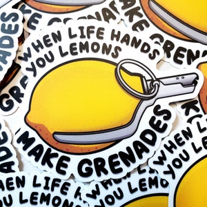 May include: A sticker featuring a yellow lemon designed as a grenade. The sticker has the text "When life hands you lemons, make grenades" in black, with a white background. The design is repeated.