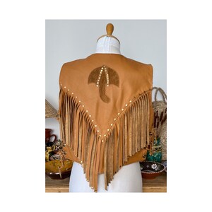 May include: A brown leather vest with fringe and a suede umbrella design on the back. The vest is decorated with gold studs.