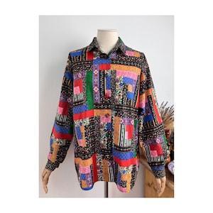Pode incluir: Uma camisa de manga comprida com botões apresentando um design de patchwork vibrante. O tecido exibe uma variedade de padrões retangulares em cores vivas como vermelho, azul, verde, amarelo e preto, com motivos florais e geométricos complexos.