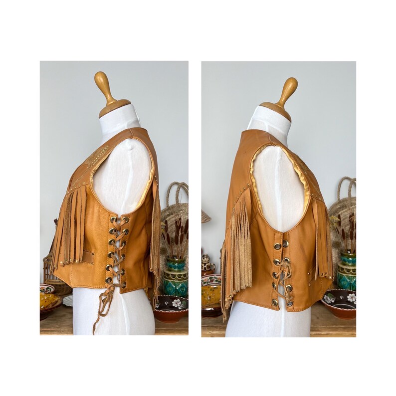 May include: A brown leather vest with fringe detailing and a lace-up front. The vest has a suede lining and is a vintage style.