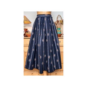 Puede incluir: Una falda azul marino con estampado floral blanco y rosa y rayas verticales. La falda es amplia y tiene la cintura fruncida.