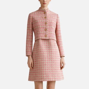 Peut inclure: Ensemble deux pièces en tweed rose et blanc. La veste a un col montant et des boutons dorés. La jupe est de style trapèze assorti. L'ensemble présente un motif géométrique.