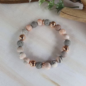 May include: A bracelet made with pink, grey, and black beads with rose gold accents.