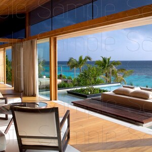 Può includere: Un soggiorno moderno con grandi finestre che si affacciano su una piscina e una vista sull'oceano. La stanza è dotata di un divano bianco, due poltrone e un tavolino da caffè in legno. La piscina è circondata da un ponte in legno e vegetazione lussureggiante.