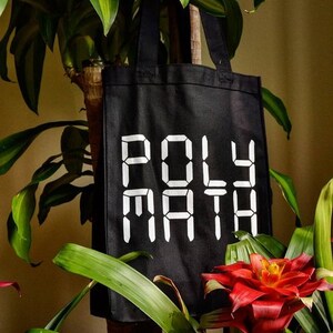 Może przedstawiać: Czarna torba typu tote z białym tekstem, który brzmi "POLY MATH" w czcionce cyfrowej.