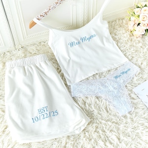 Può includere: Pigiama bianco con testo ricamato blu. Il set include una canotta, pantaloncini e un perizoma. La canotta e il perizoma hanno ricamato il nome "Mrs. Myers". I pantaloncini hanno ricamato il testo "EST 10/22/25".