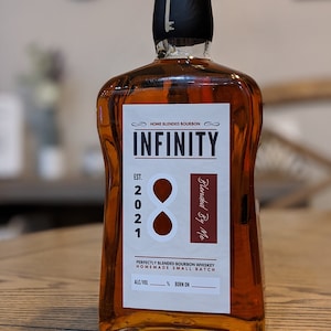 May include: A bottle of amber bourbon whiskey with a black cap and a key design. The label reads "INFINITY" and "Blended By Me." The bottle is labeled "Home Blended Bourbon" and "Perfectly Blended Bourbon Whiskey Homemade Small Batch."