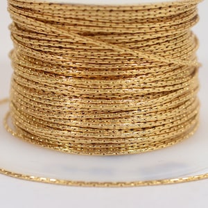 May include: A spool of gold-colored metallic cord. The cord is thin and has a textured surface.