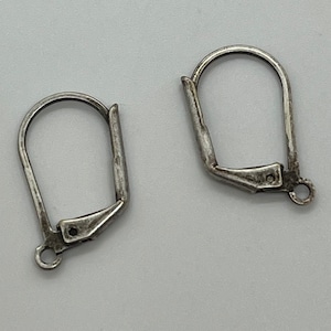May include: Two silver-toned earring hooks with a simple design. The hooks are made of metal and have a smooth finish.