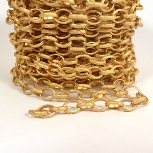 May include: A close-up of a gold chain with a textured oval link design. The chain is coiled up and a single strand is extended out.