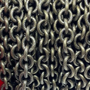 May include: A close-up of a silver chain with a twisted rope design. The chain is made of metal and has a shiny finish.