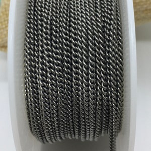 May include: A spool of black twisted wire cord. The cord is wound tightly around a white plastic spool.