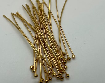 May include: A pile of gold-colored head pins with round heads. The pins are about 1 inch long.