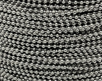 May include: A close-up of a silver chain made of small, round beads. The chain is tightly wound into a coil.