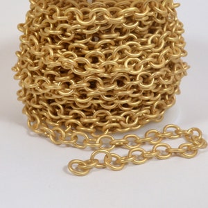 May include: A close-up of a gold chain, coiled and uncoiled, showing the individual links. The chain is made of a smooth, shiny metal.