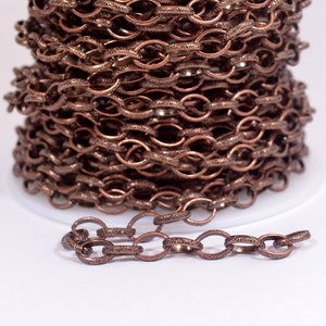 May include: A spool of copper-colored chain with an ornate design. The chain is made of small, oval-shaped links.