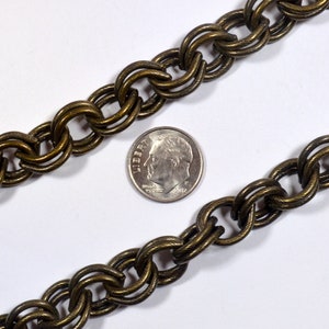 May include: A close-up of a gold-toned chain with a twisted design. The chain is about the size of a US dime.