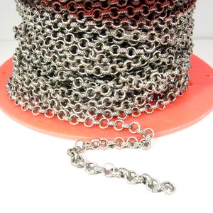 May include: A spool of silver chain with a textured finish. The chain is coiled on a red base.