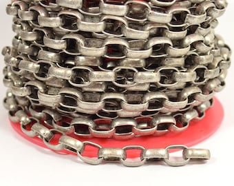 May include: A spool of silver-colored chain with oval and rectangular links. The chain is coiled around a red plastic spool, with a portion of the chain unraveled at the bottom. The chain has a vintage or antique appearance.