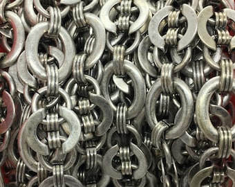 May include: A close-up of a silver chain made of interlocking rings. The chain is coiled and appears to be made of metal.