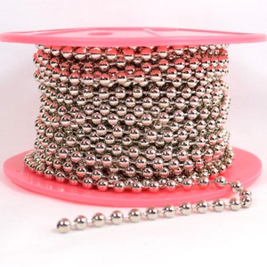 May include: A spool of silver metal chain with round links. The chain is wound around a pink plastic spool.