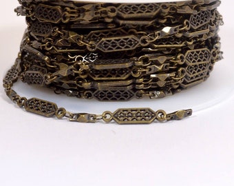 Könnte beinhalten: Eine Spule mit antiker goldfarbener Kette mit geometrischem Muster. Die Kette ist aus Metall und hat ein filigranes, kompliziertes Design.
