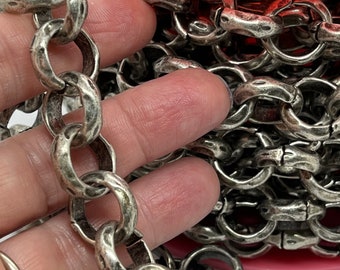 May include: A close-up of a silver chain with a textured finish. The chain is wound around a pink spool.